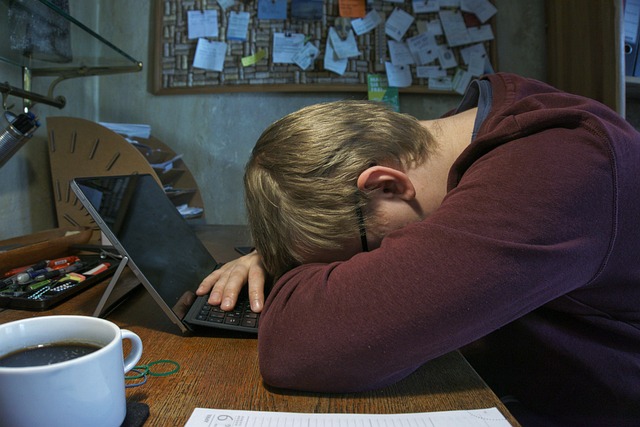 Project reporting problems. A project manager with his head on the desk surrounded by coffee and paperwork.